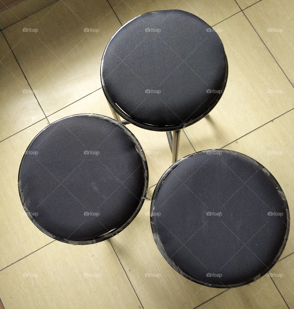 The tops of sitting stools placed in triangular shape on the tiled floor