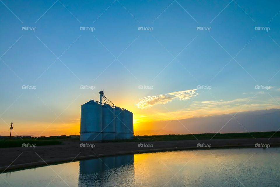 Scenic view of silos at sunset