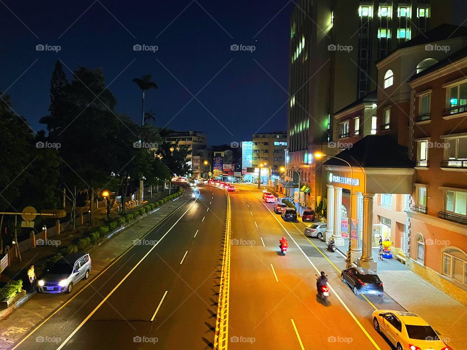 An empty intersection at nighttime in Changhua, Taiwan. There are buildings in the distance, and to both sides. 