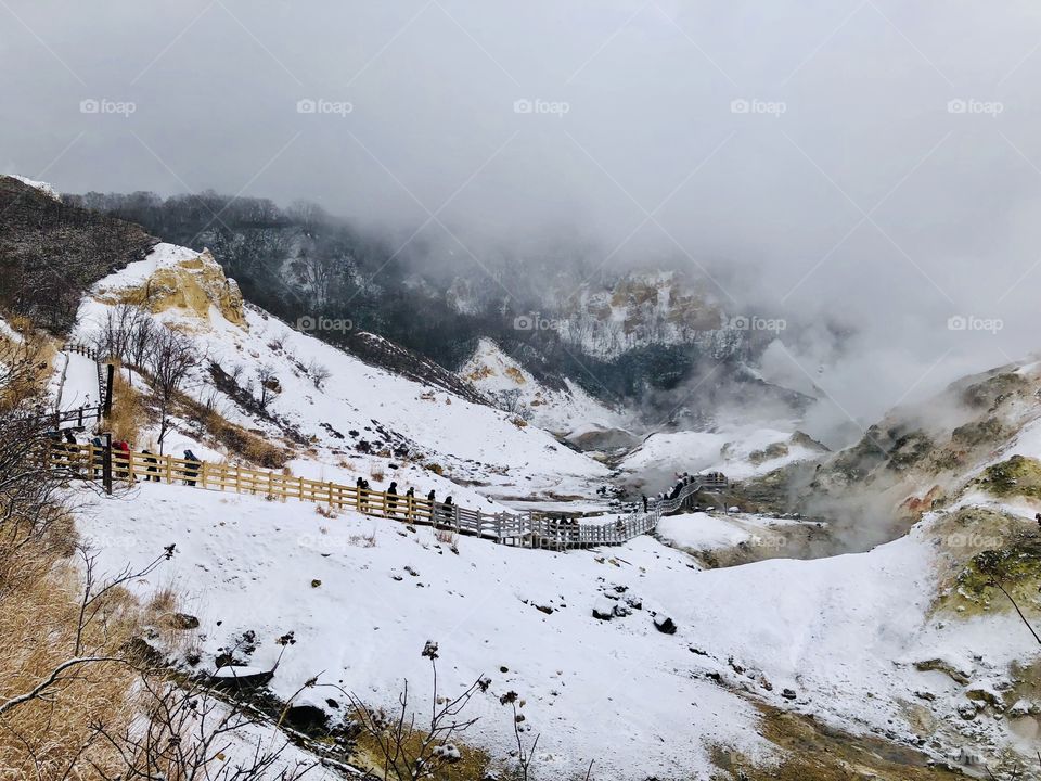 Jigokudani or Hell Valley wooden walkway bridge in the town of Noboribetsu Onsen, hot steam vents, sulfurous streams and other volcanic activity, hot spring waters, Hokkaido, Japan, winter with snow