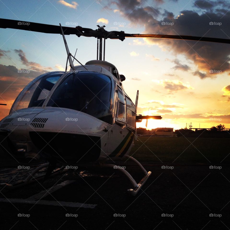 A Bell 206 Helicopter on the ramp with the sun setting in the background in Kingston , Jamaica 
