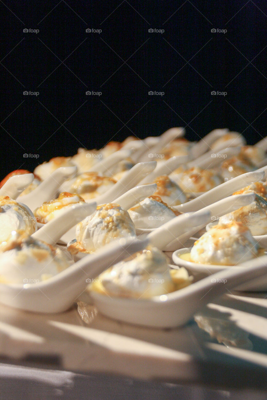 Rows of individual serving meringue desserts line a table at a reception