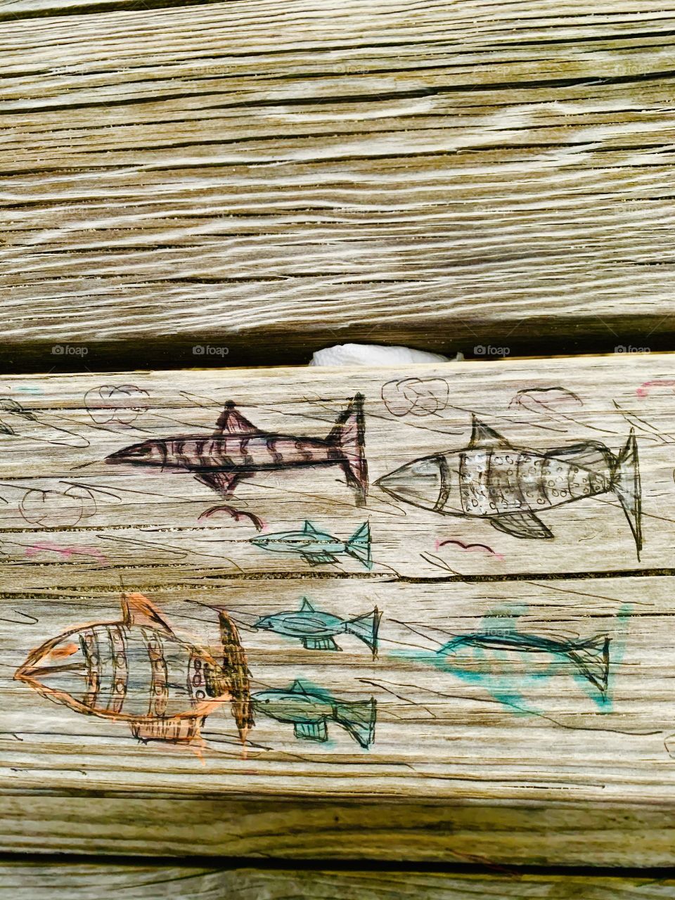 Someone carved these designs in a wooden picnic table. Carving is the act of fashioning or producing by cutting into or shaping solid material, as wood. a carved design or figure.