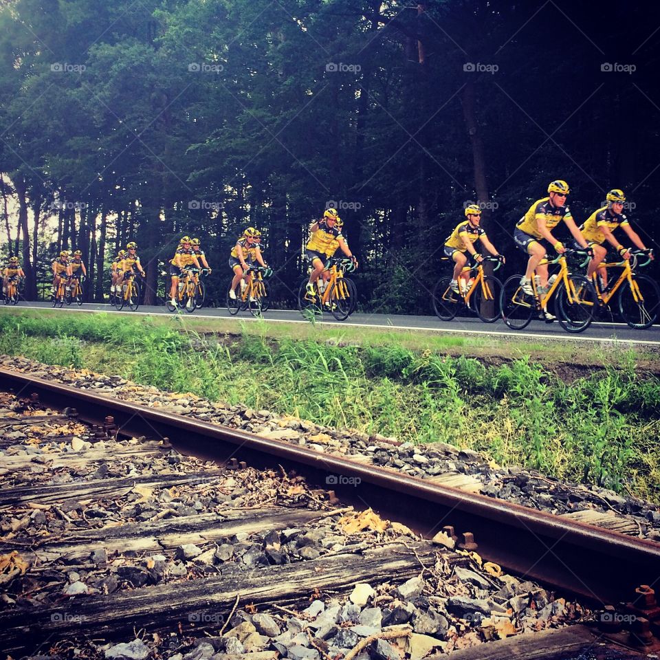 Bike team in yellow clothes next to railroad