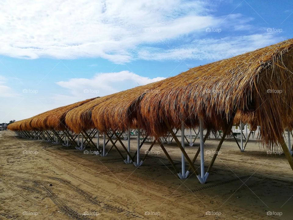 row of straw parasols on the empty beach