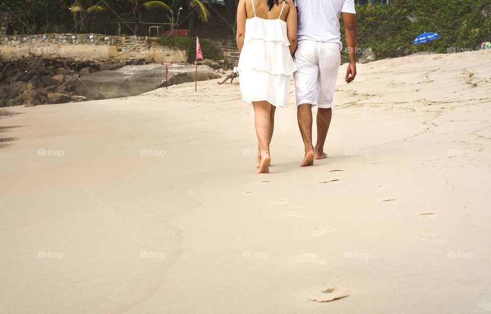 Couple relaxing walking on sand beach leaving footprints in the sand