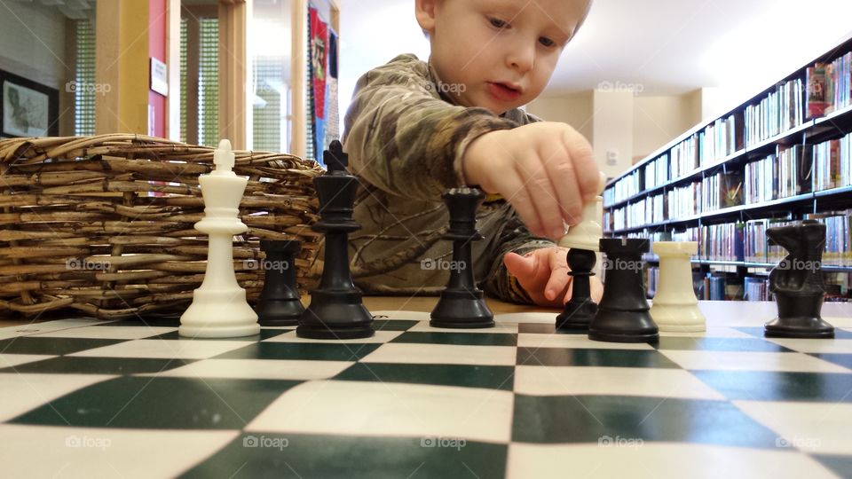 boy playing with black and white chess pieces