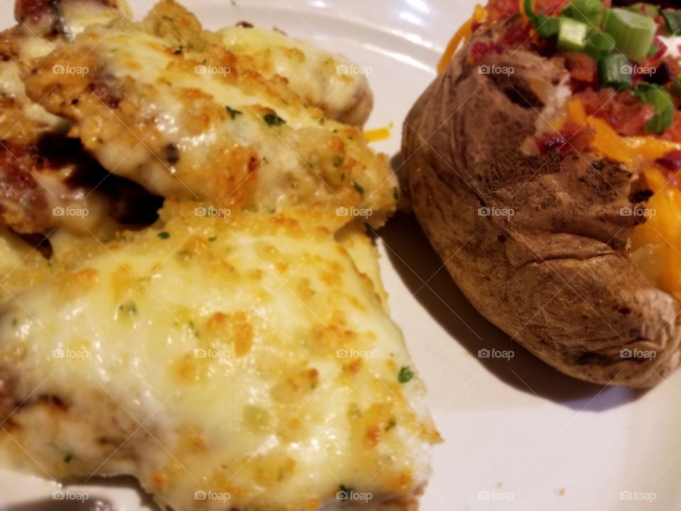Parmesan Crusted Chicken Breasts with a Baked Potato on a White Plate