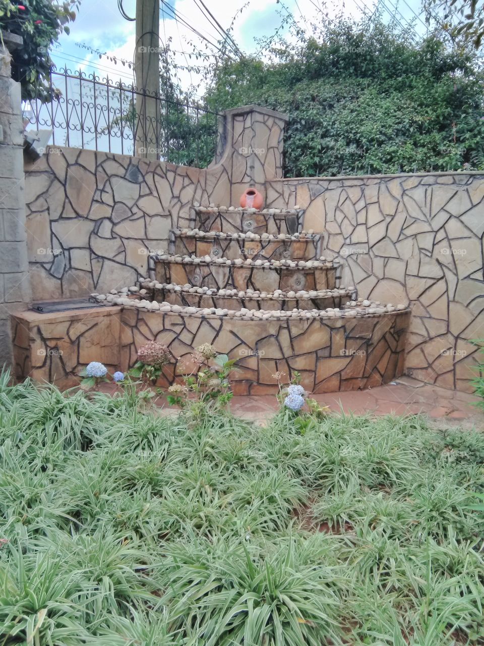 This is a beautiful modern fountain with pebbles on top. It has been build at a corner in a modern home compound.