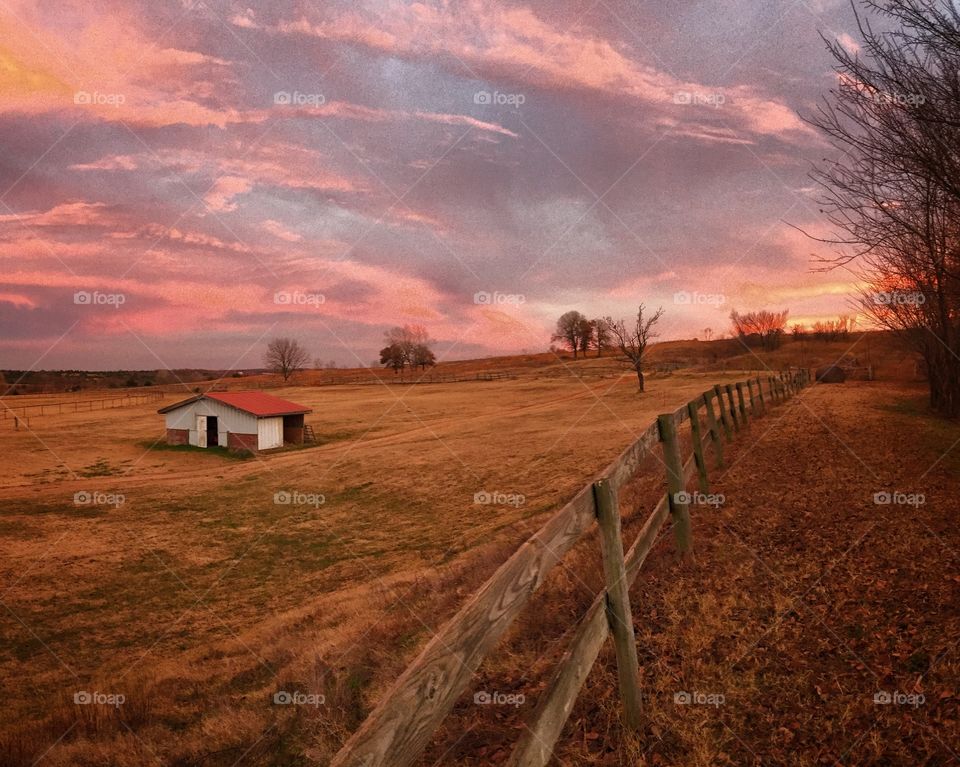 Barn in a valley field at sunset