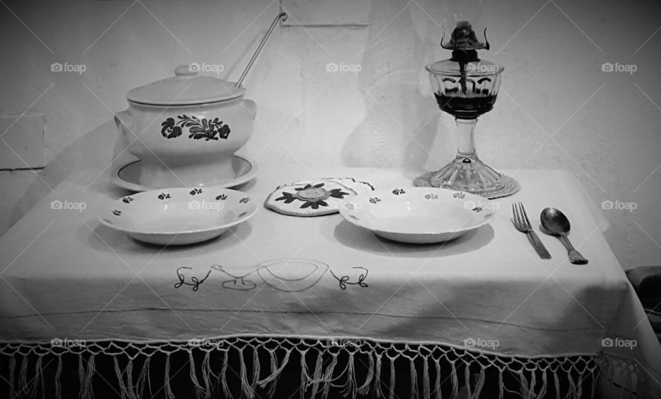 in a recreated Portuguese kitchen in a musuem shows a simple place setting. The table cloth was hand embroidered and showed how the lamp oil was the only lighting