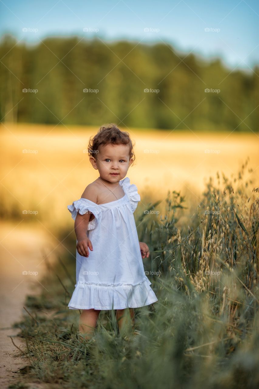 Little girl in rye field at summer evening 