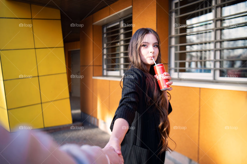 Dark hair girl drinks coca cola. Long brown hair. Teenager. Young fashion style. Follow me to