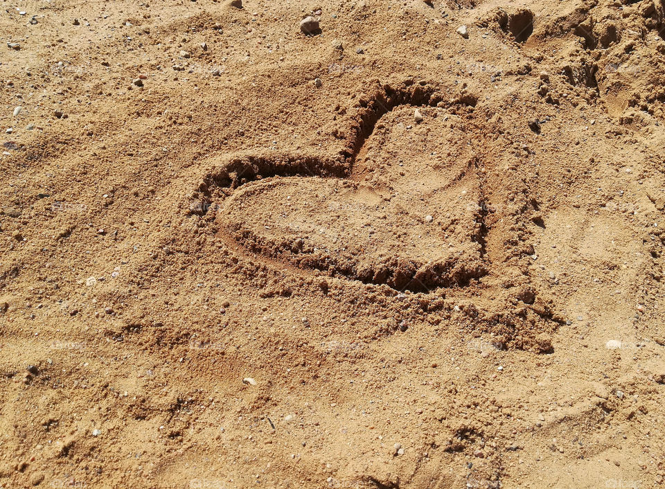 heart drawn in the sand; sign of a heart on the sand; summer, background, close-up; heart sighn, heart-shaped