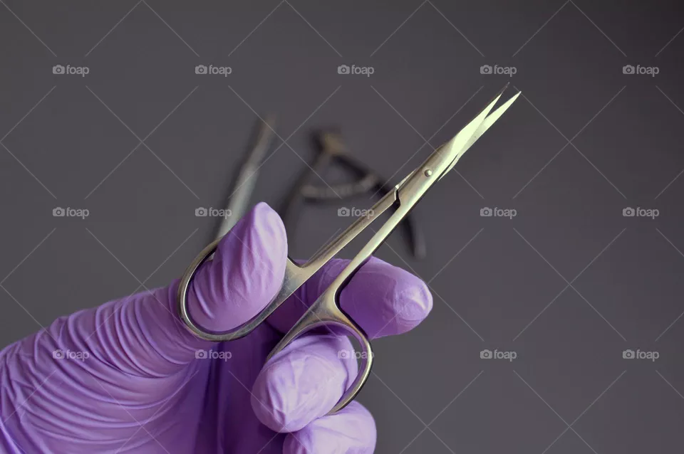 Manicure tools are held by a manicurist in rubber gloves