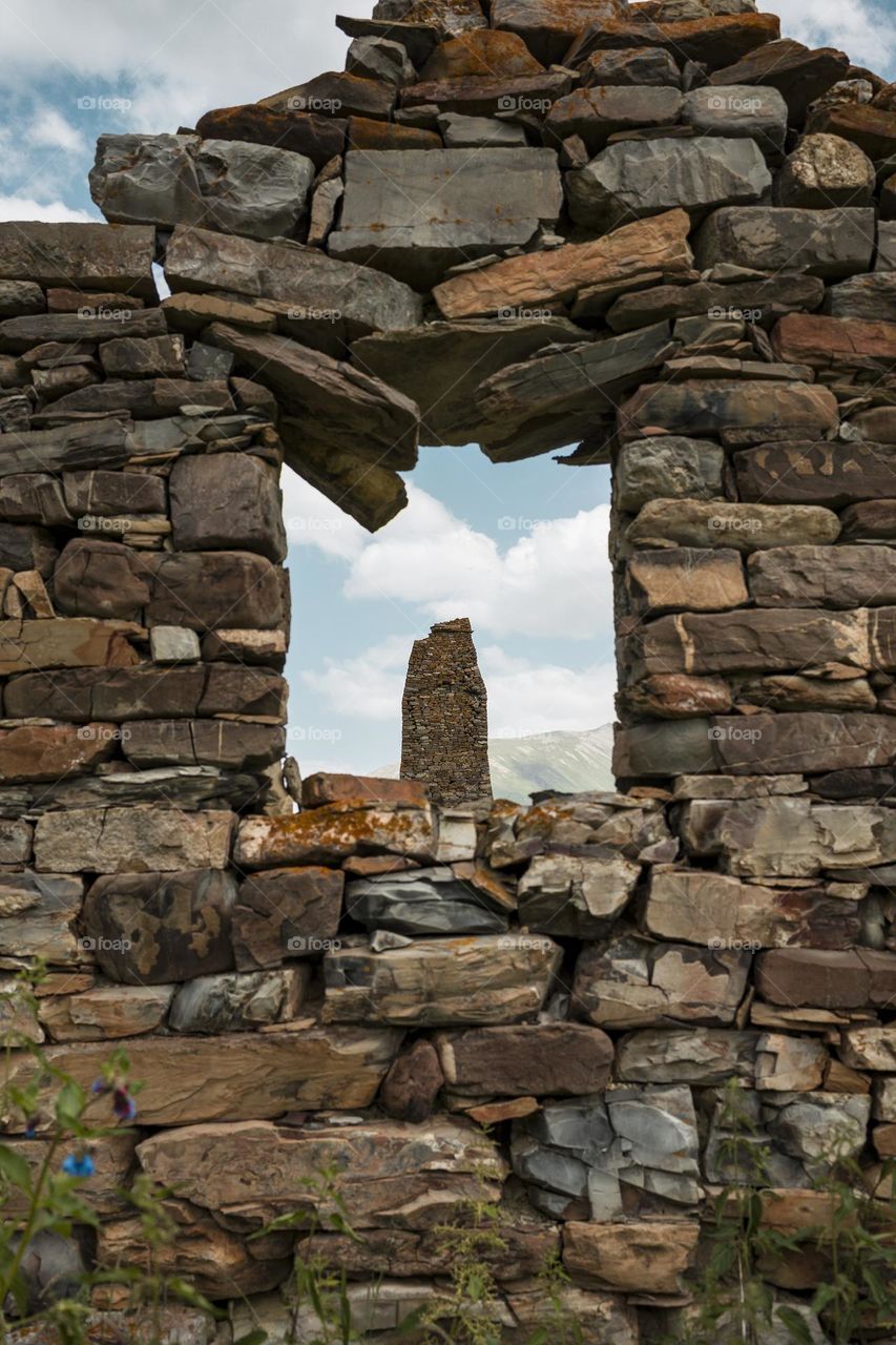 Ancient ruined medieval tower  against cloudy sky background . North Ossetia Alania , Russia
