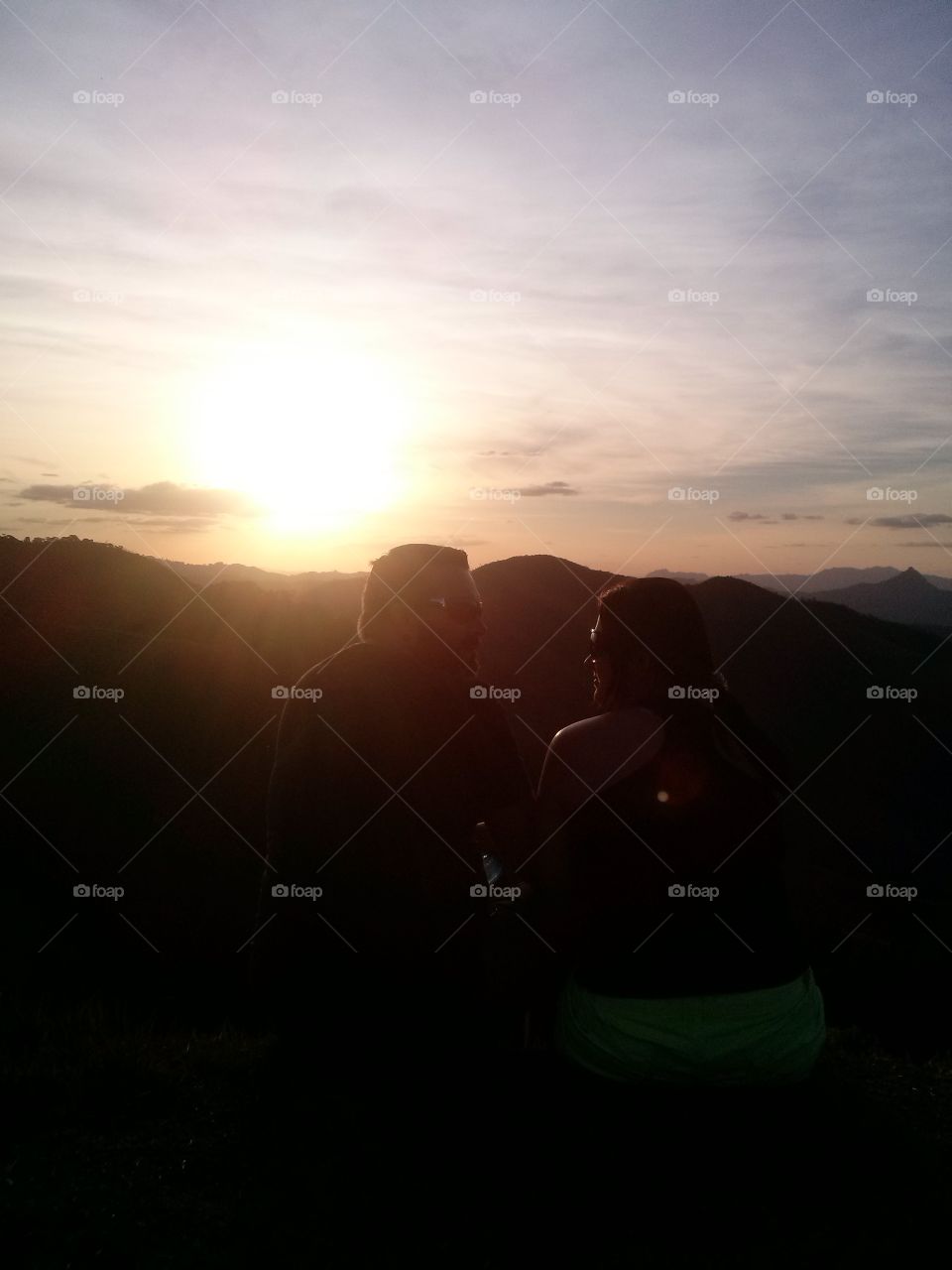 Couple sitting on mountain during sunset