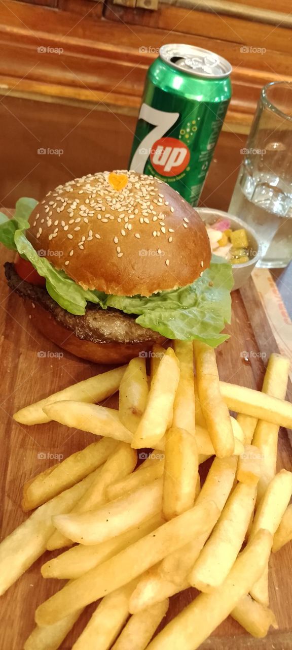 hamburguesa completa de lechuga, tomate y  carne con papás fritas y una bebida 7up.