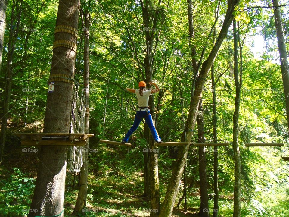 Woman climbing the trees in an adrenalin-adventure park