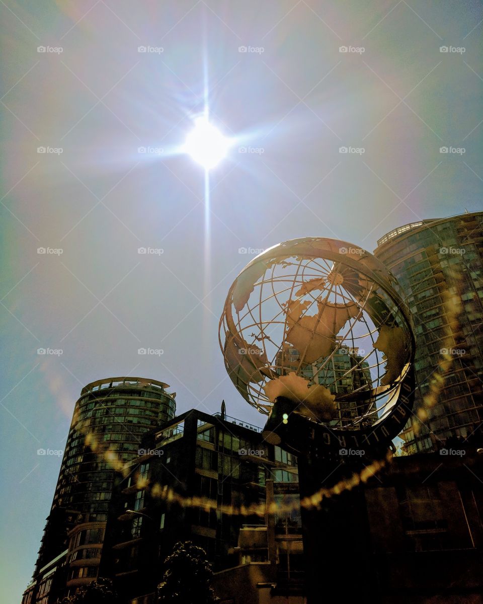 Beautiful Sun Touched Metal Globe with Buildings Behind