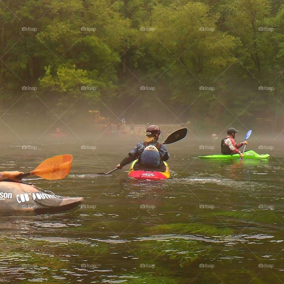 kayakers paddling on the river through mist