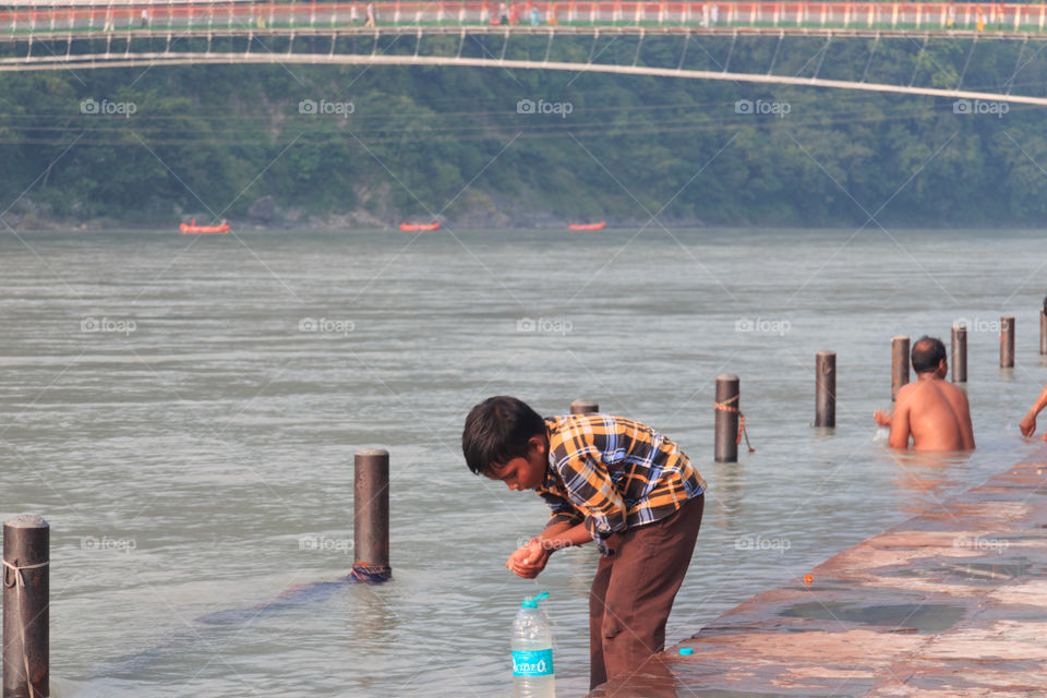 A boy filling up ganga river water in a bottle