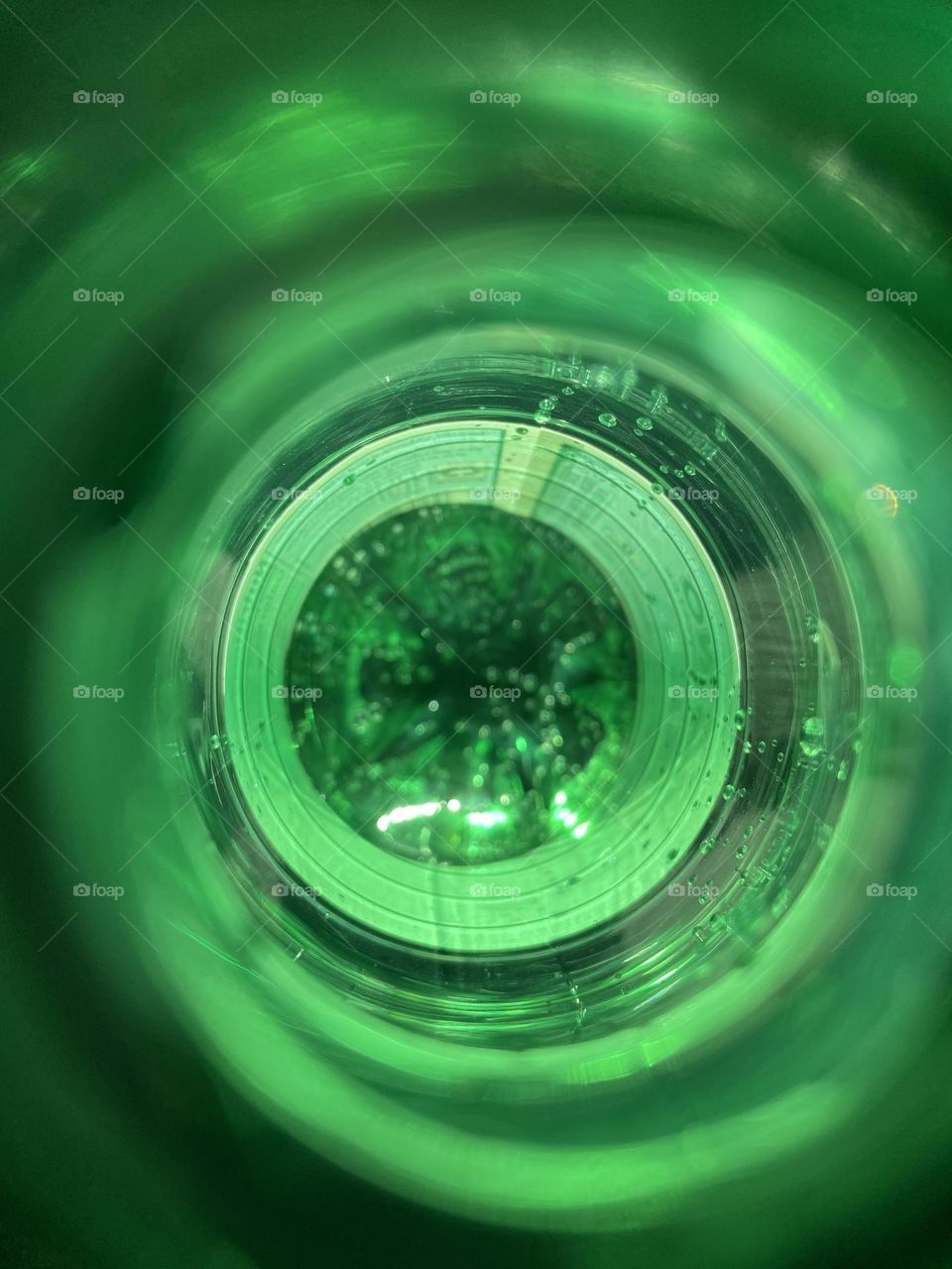 Concentric green rings surround a darker sparkly center in this photo of the inside of a San Pellegrino mineral water bottle. 