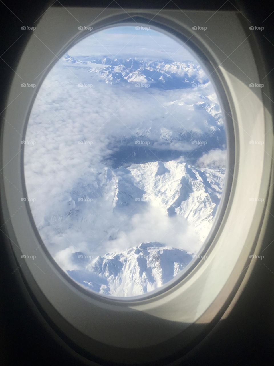 Amazing Swiss snowy mountains view from airplane window, plane porthole view, Switzerland snowy mountains 