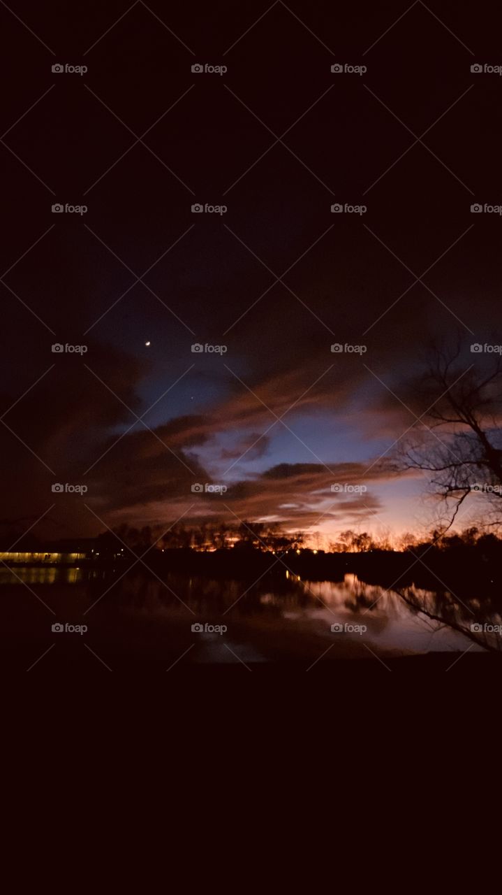 Moonlit Twilight has Complex Mixture of cascading Cloud inter mixing with Moon-shadows. Reflections-of Clouds and Colors above the Lake Waters are Visible even though Night Is Near to Be.