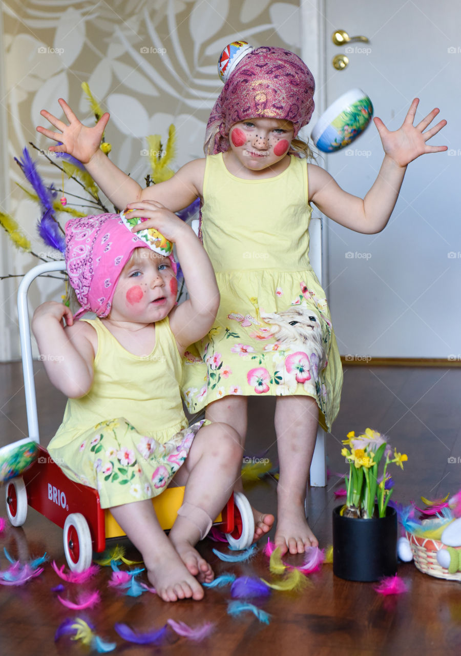 Two young sisters having fun infront of the camera with easter theme.