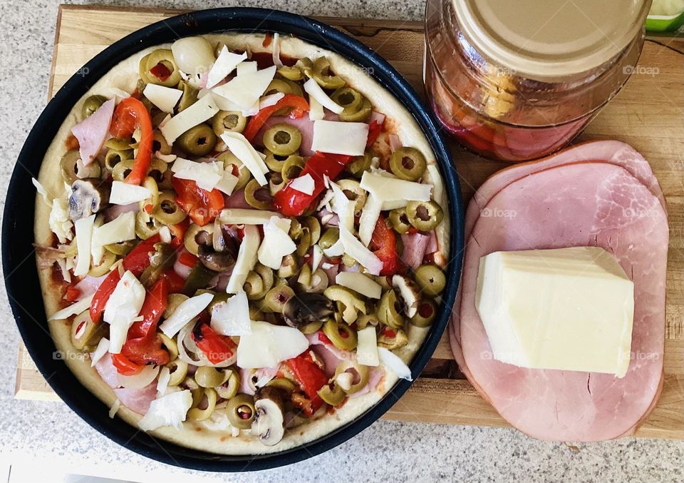 pizza preparation with cheese olives red peppers ham 