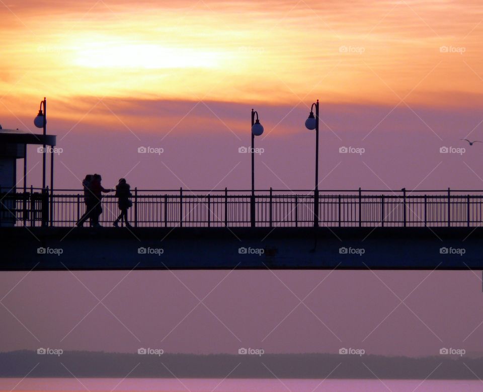 Silhouette of people on pier against sky during sunset in Międzyzdroje, Poland.