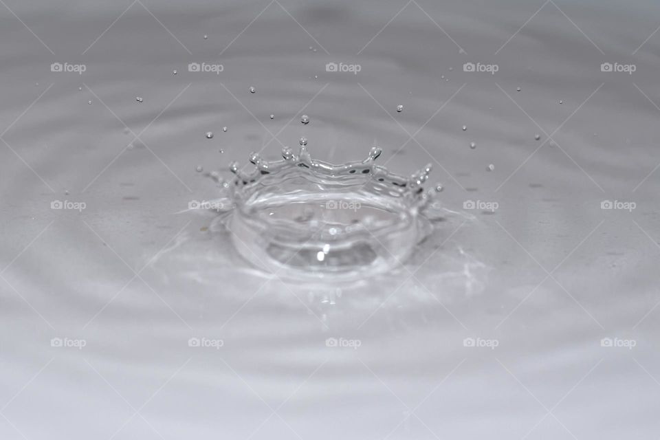 Falling water droplet creating round splash.