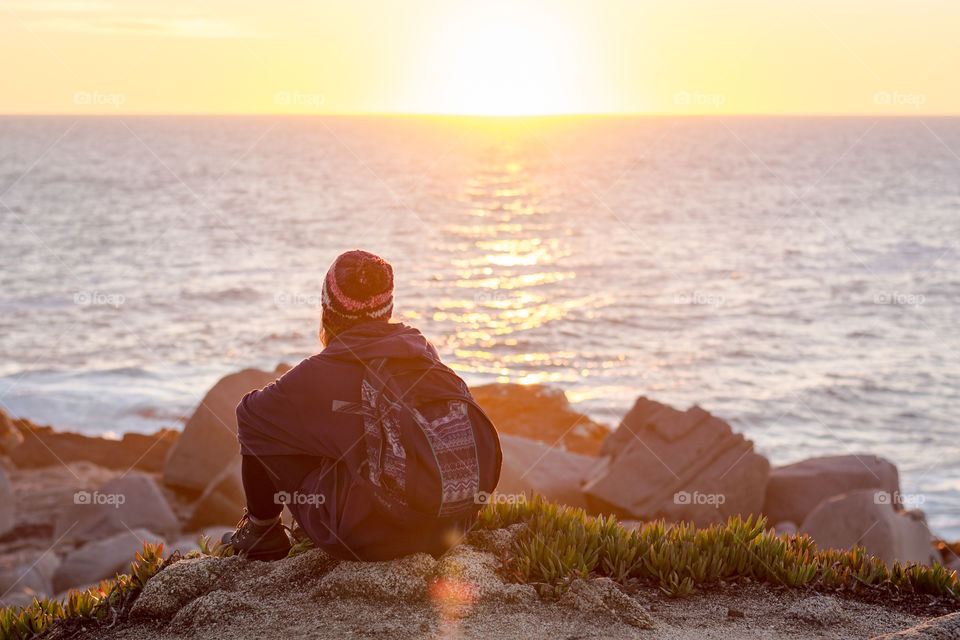 Young woman sitting down watching the sunset 