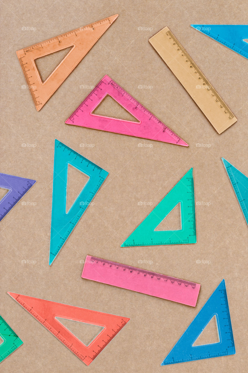 Overhead shot of arranged colorful set squares on brown paper