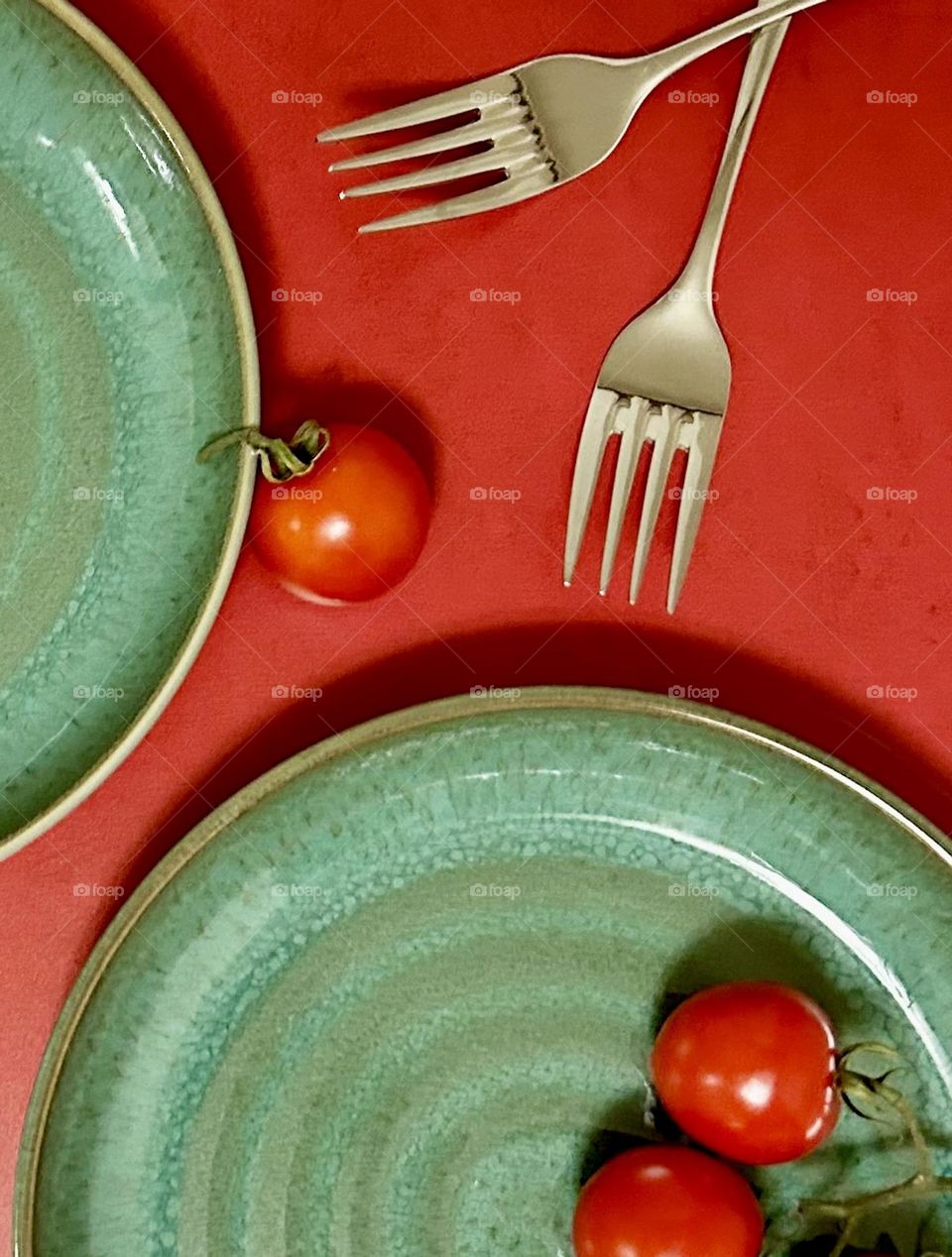 Complimentary flat lay, green plates with red tablecloth and cherry tomatoes 