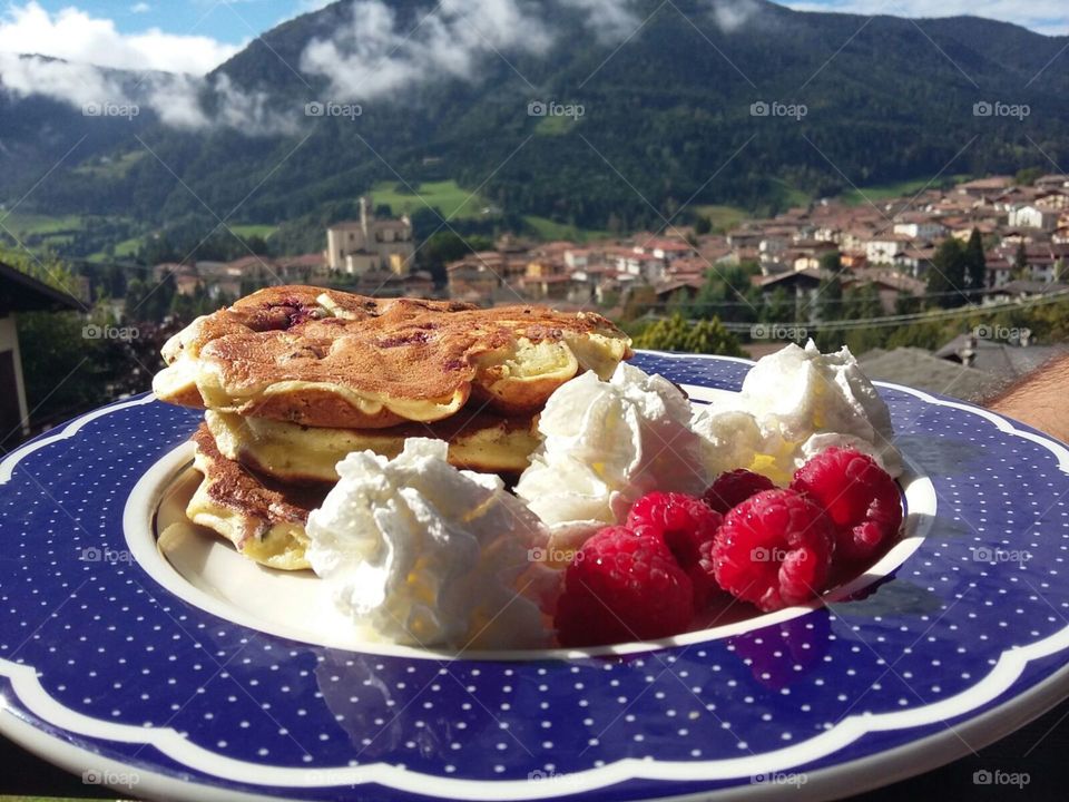 blueberry pancake, whiped cream and raspberries, breakfast in the Alps