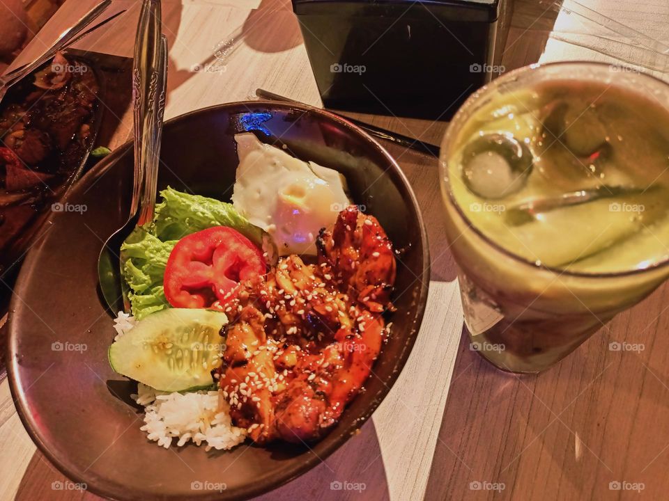 Grilled chicken with rice, salad, tomato, tempeh and sambal (Indonesia chilli sauce) on table