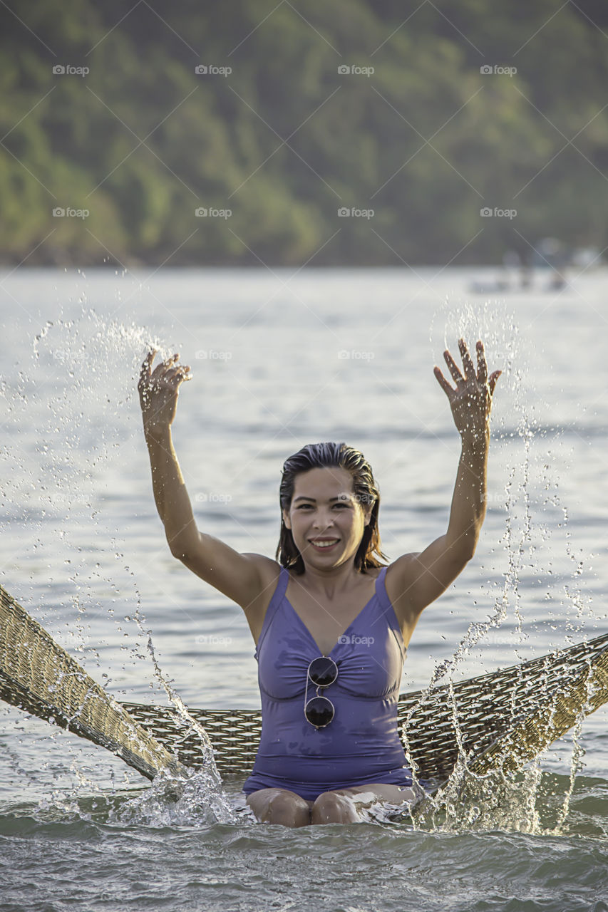 Portrait of Asian woman wearing a swimsuit on Hammock swing in sea.