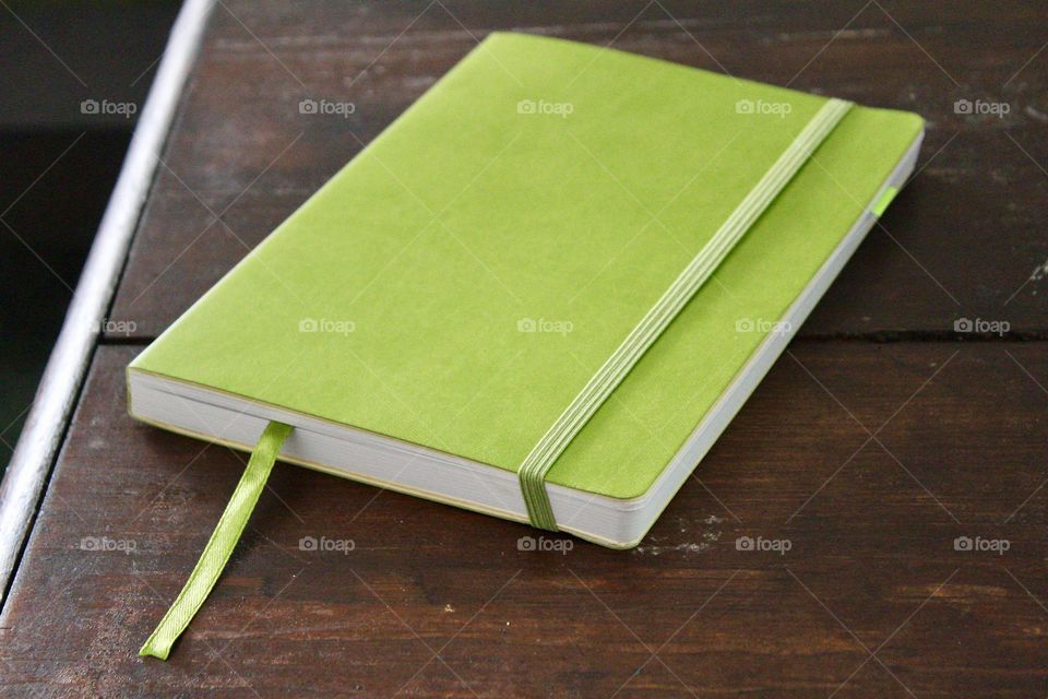 Close-up of green diary on wooden table