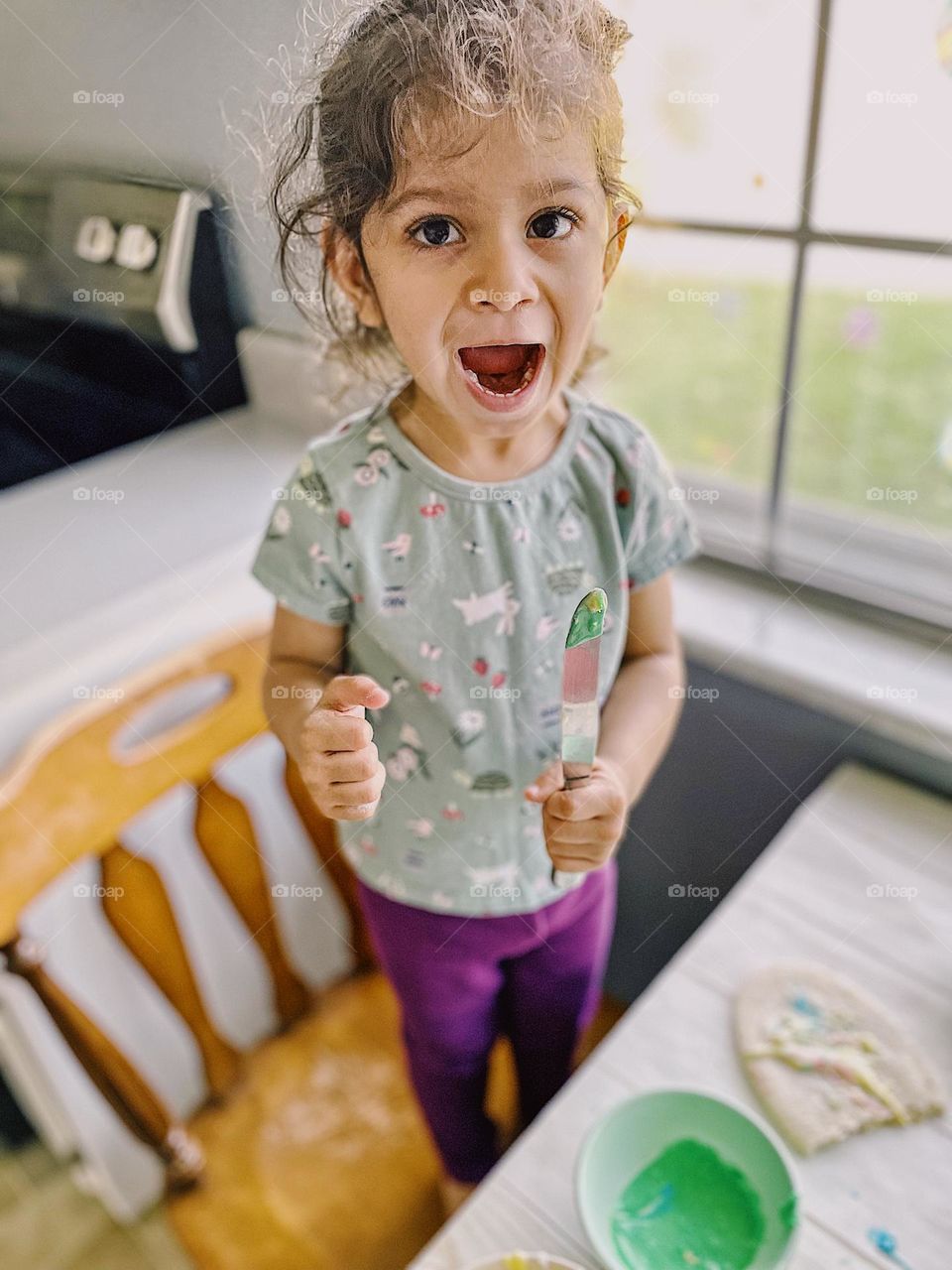 Little girl surprised with Easter cookies, toddler girl excited to decorate Easter cookies, making Easter sugar cookies for the celebration, Easter traditions with family, making memories in the kitchen 