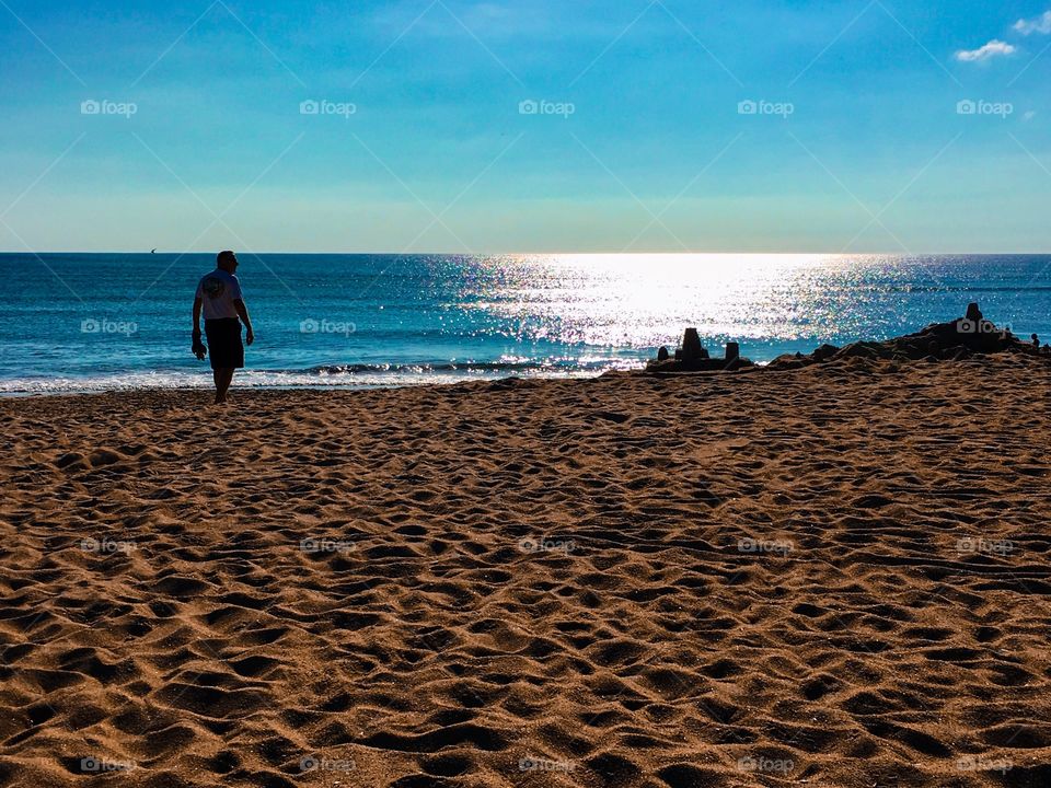 Beach walk with blue water, powdered sand, and sand castles. 