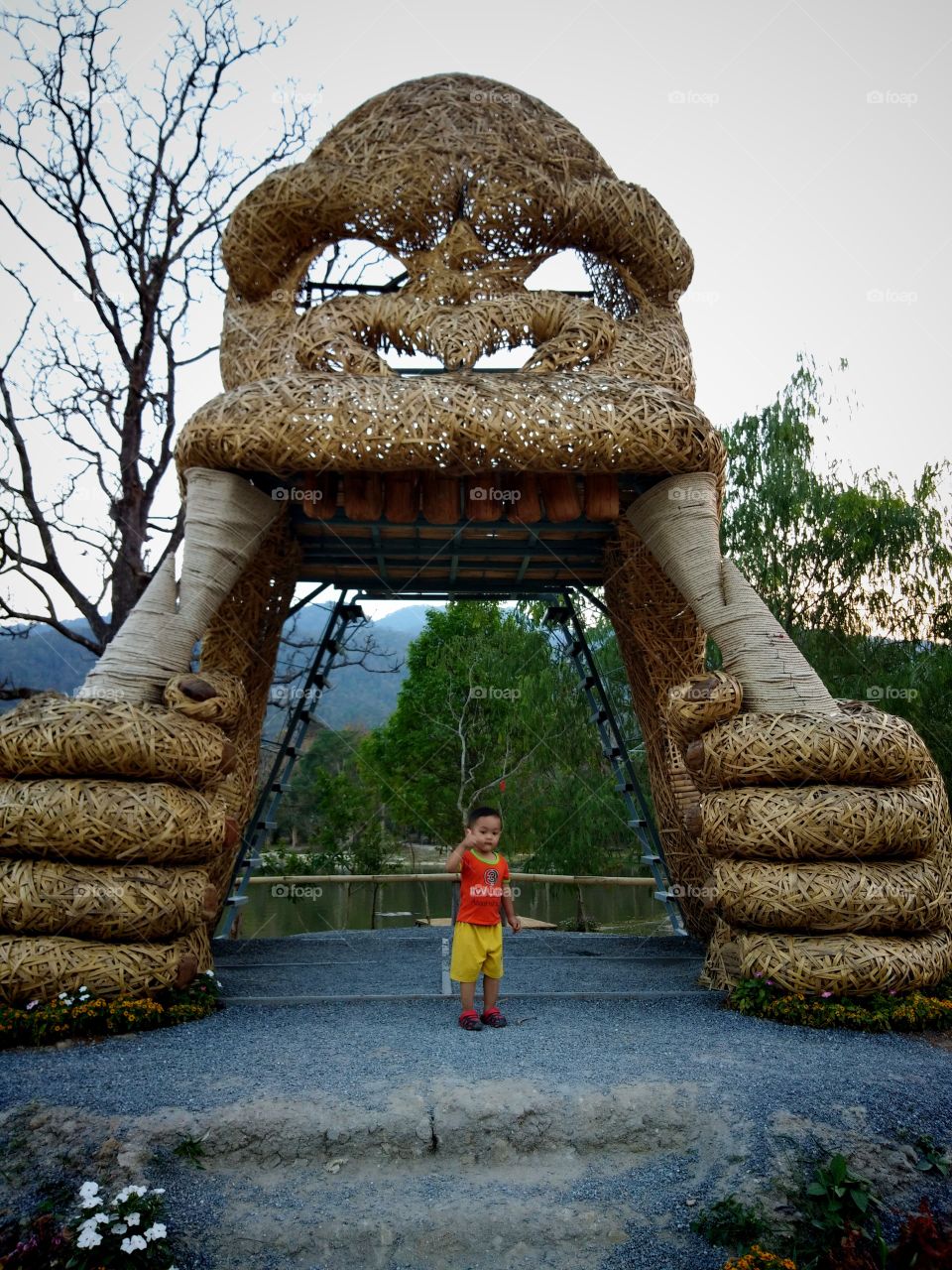 Thai cute boy taking a photo with giant King Kong  straw statues .