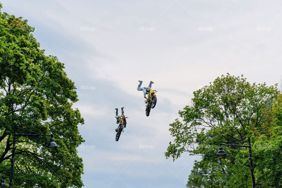 Motocross riders fly high above trees 