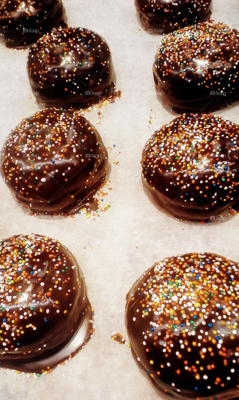 Big round doughnuts/donats with 
chocolate glaze and colorful candies on