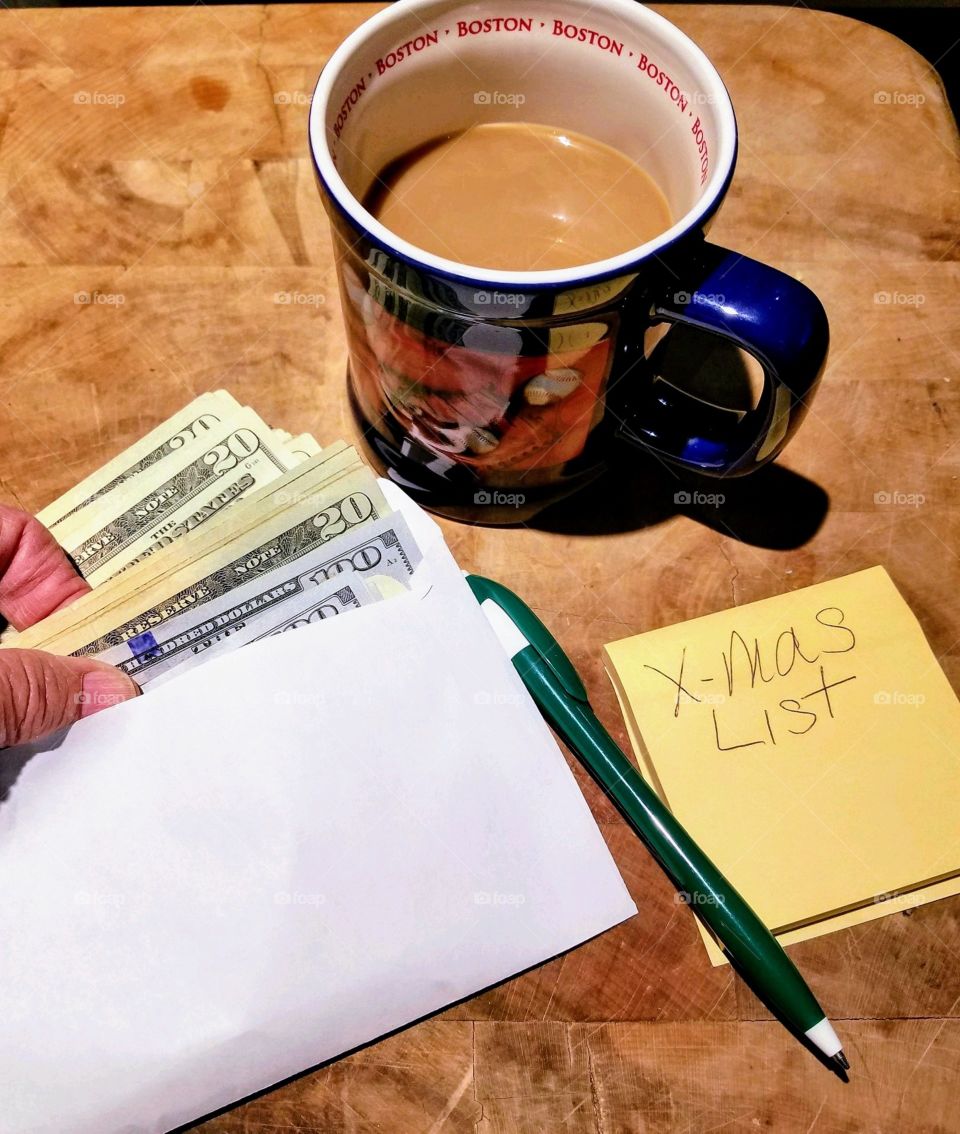 Christmas shopping list. counting money in envelope, Cup of coffee & pad of paper.
Making shopping list!