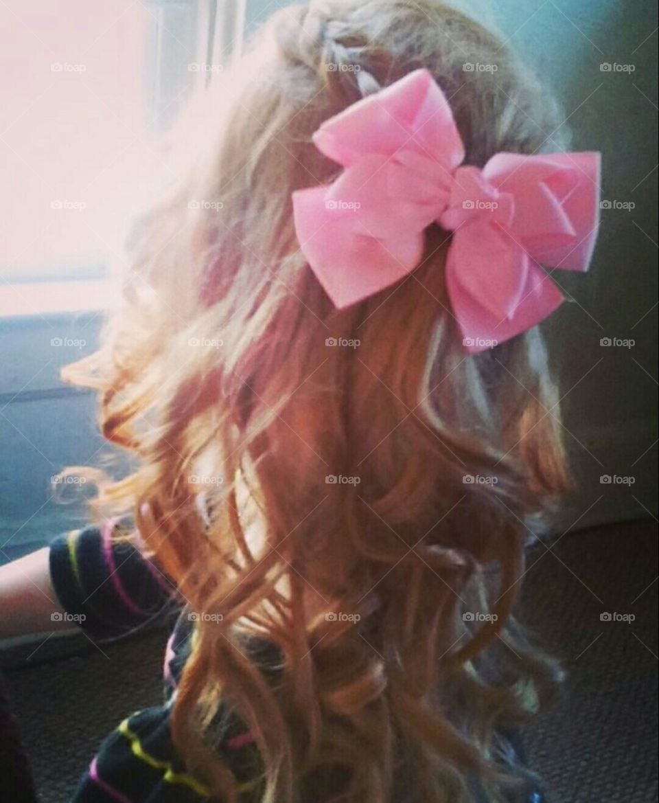 curly hair with braids tied back in a bow.