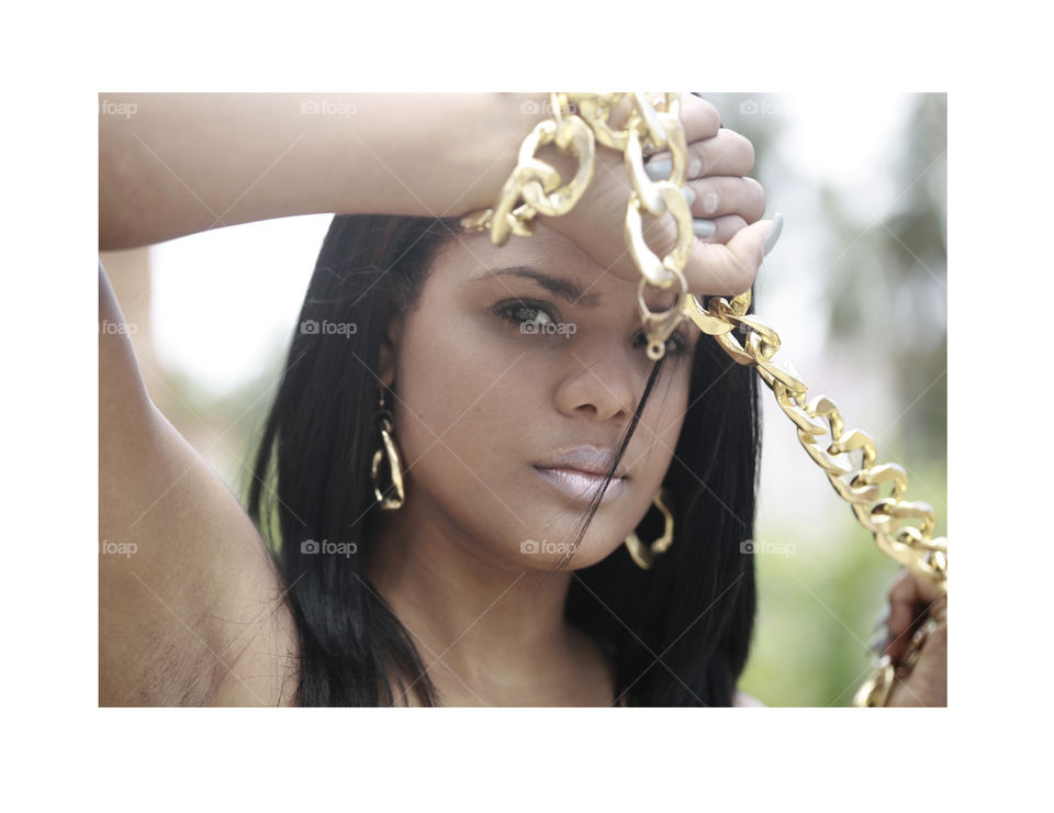 Latin girl with a golden chain. girl holds big golden chain in front of her face, fashion beauty photo