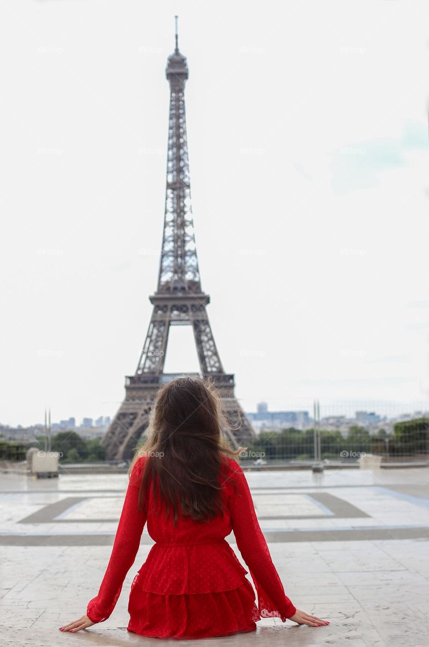 Faceless brunette woman seats alone on the Eiffel tour background 