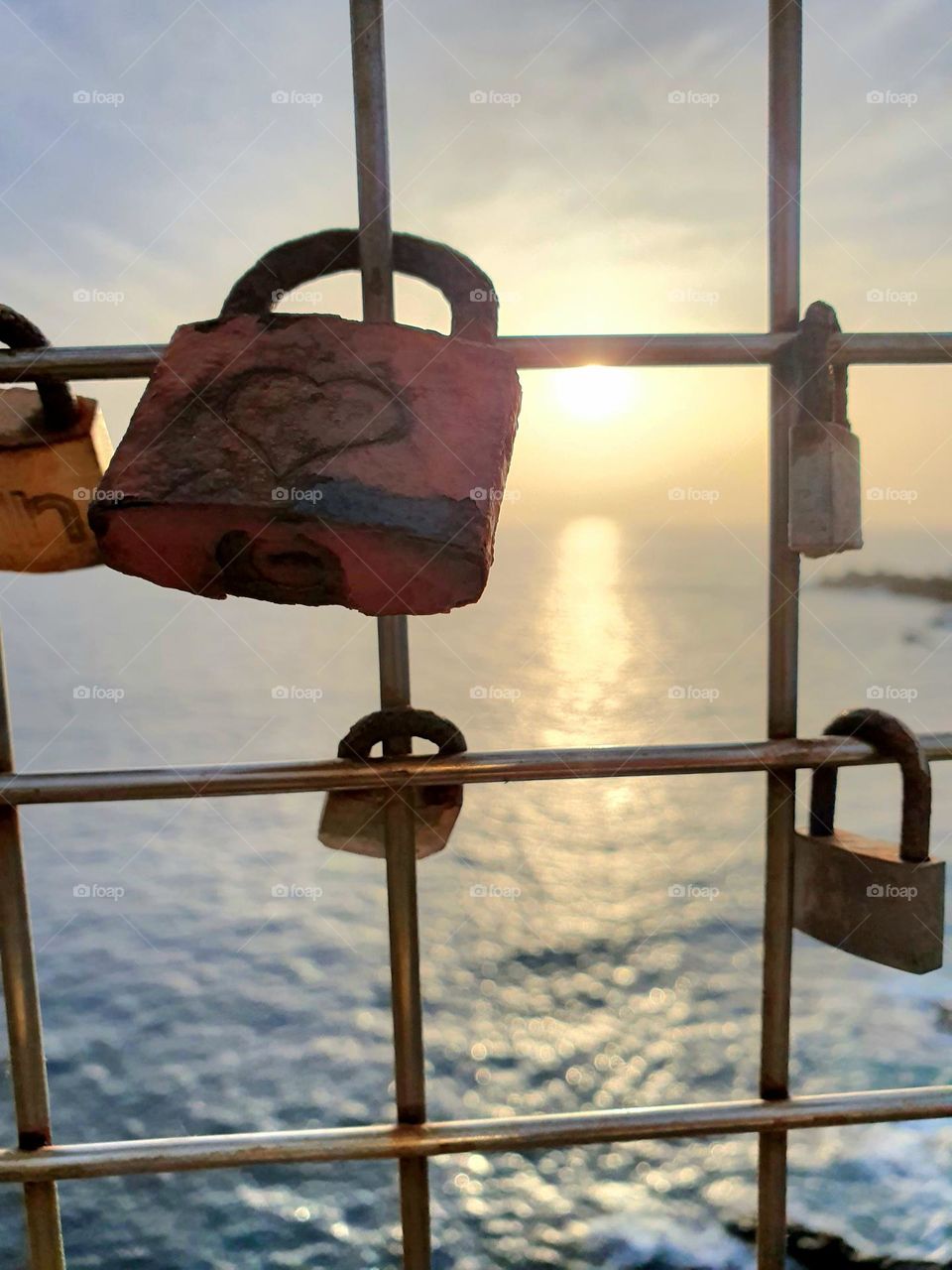 Padlocks- rusted love locks on the iron gate with sunset in the background